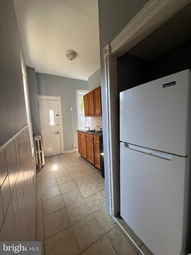 kitchen with dishwasher, radiator, sink, light tile patterned floors, and white fridge