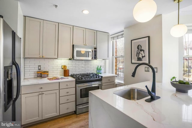 kitchen featuring gray cabinets, decorative backsplash, stainless steel appliances, and a sink