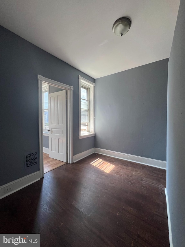 unfurnished room with dark wood-type flooring