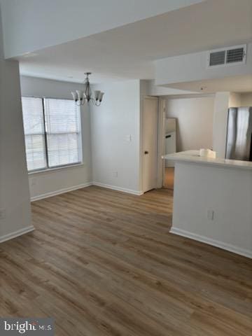 unfurnished living room featuring an inviting chandelier and dark wood-type flooring