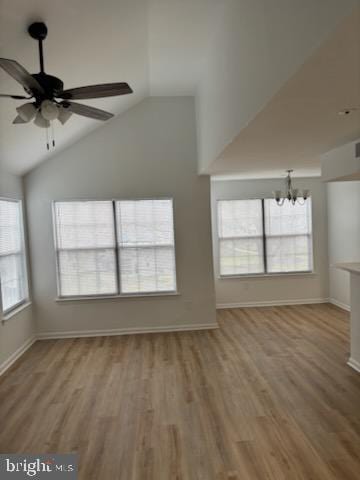 unfurnished living room featuring vaulted ceiling, wood-type flooring, and a healthy amount of sunlight