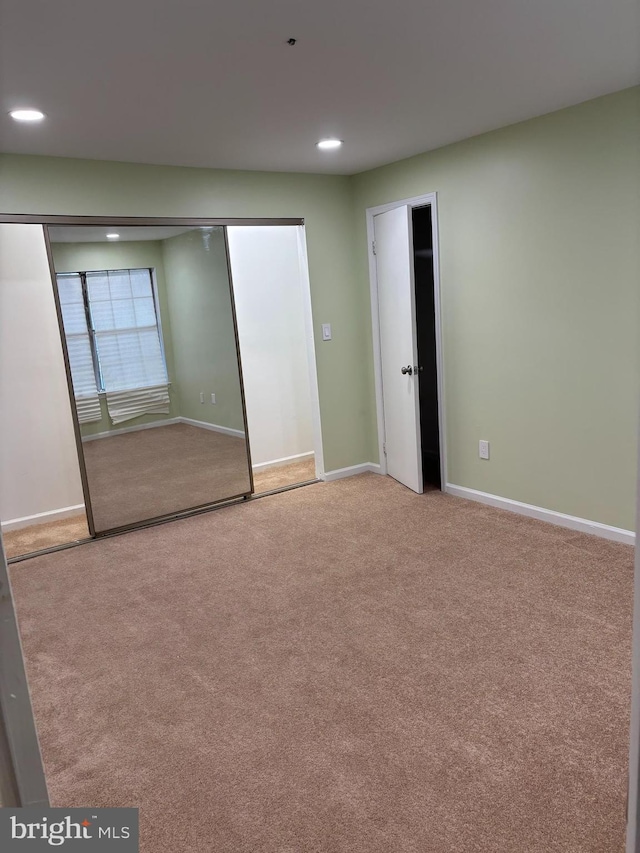 unfurnished bedroom with light colored carpet and a closet