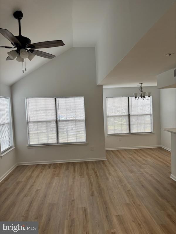 unfurnished living room featuring lofted ceiling, ceiling fan with notable chandelier, and wood-type flooring