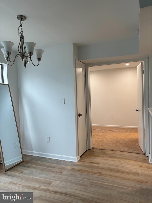 unfurnished dining area featuring an inviting chandelier and light hardwood / wood-style floors