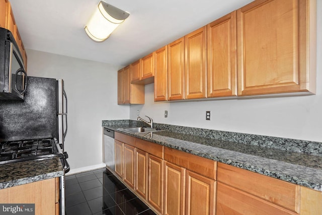 kitchen with sink, dark tile patterned flooring, dark stone counters, and black appliances