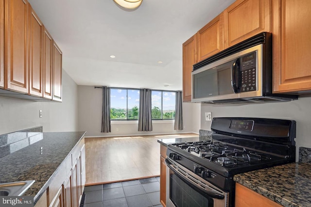 kitchen featuring dark stone counters, dark hardwood / wood-style floors, and black gas range oven