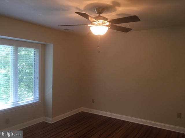 spare room with a healthy amount of sunlight, ceiling fan, and dark wood-type flooring