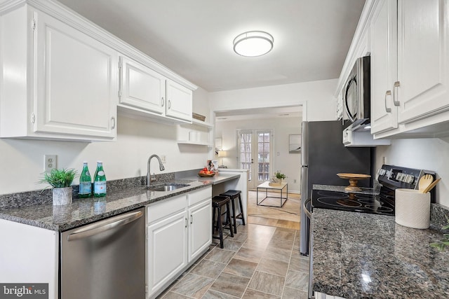 kitchen featuring sink, white cabinets, french doors, dark stone counters, and appliances with stainless steel finishes