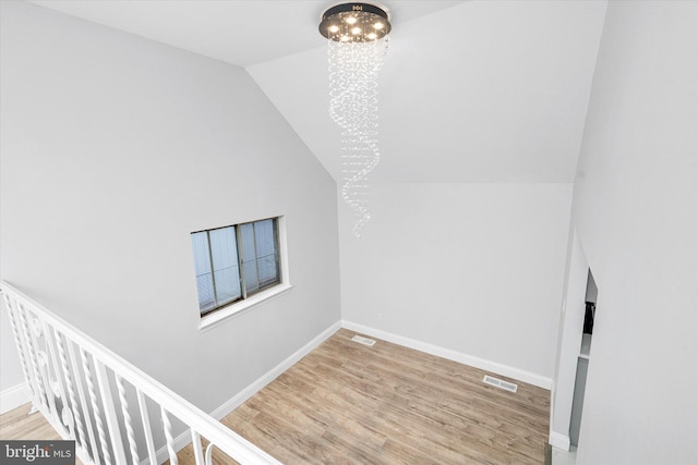 additional living space with a chandelier, lofted ceiling, and hardwood / wood-style flooring