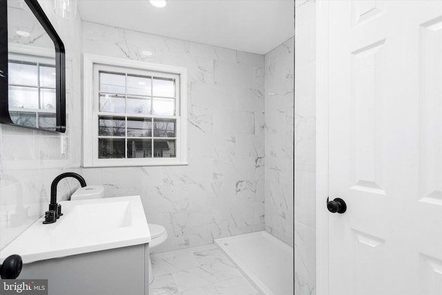 bathroom featuring vanity, toilet, a shower, and tile walls