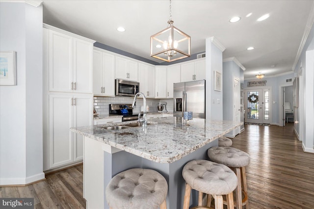 kitchen with a center island with sink, white cabinets, and appliances with stainless steel finishes