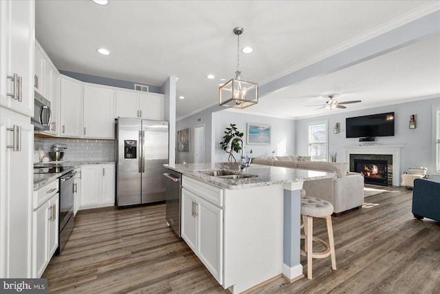 kitchen with white cabinetry, sink, dark hardwood / wood-style flooring, a kitchen island with sink, and appliances with stainless steel finishes