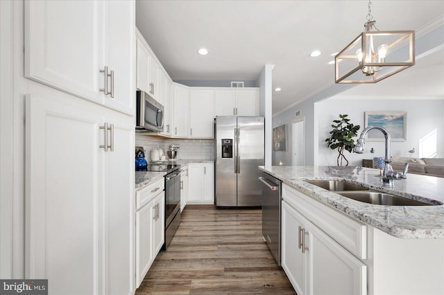 kitchen with stainless steel appliances, sink, white cabinets, hardwood / wood-style floors, and hanging light fixtures