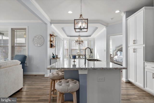 kitchen with white cabinets, sink, an island with sink, and dark wood-type flooring