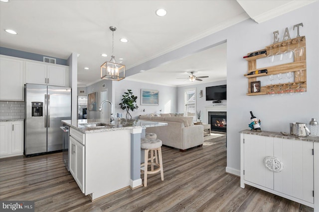 kitchen featuring sink, a kitchen island with sink, white cabinets, ceiling fan with notable chandelier, and appliances with stainless steel finishes