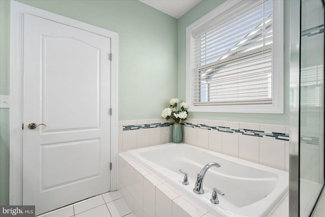 bathroom with tile patterned flooring and tiled bath