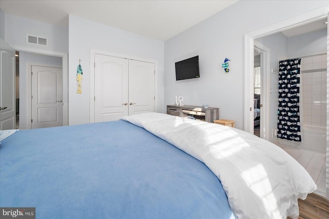 bedroom featuring light wood-type flooring, connected bathroom, and a closet