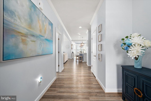 hall with a chandelier, crown molding, and wood-type flooring