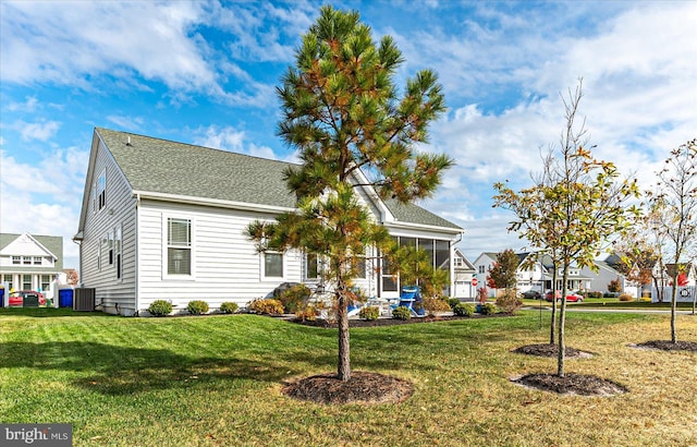 view of front of house with a sunroom, central AC unit, and a front yard