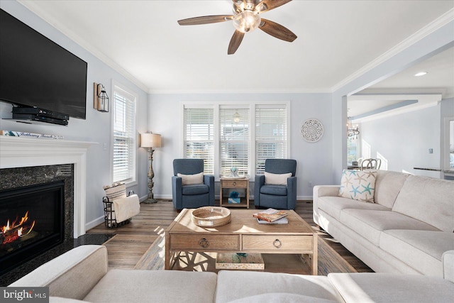 living room featuring a high end fireplace, crown molding, ceiling fan with notable chandelier, and dark hardwood / wood-style floors