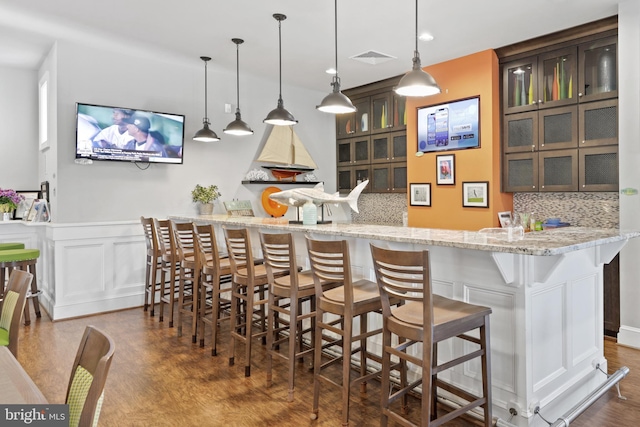 bar featuring decorative backsplash, dark brown cabinets, and decorative light fixtures