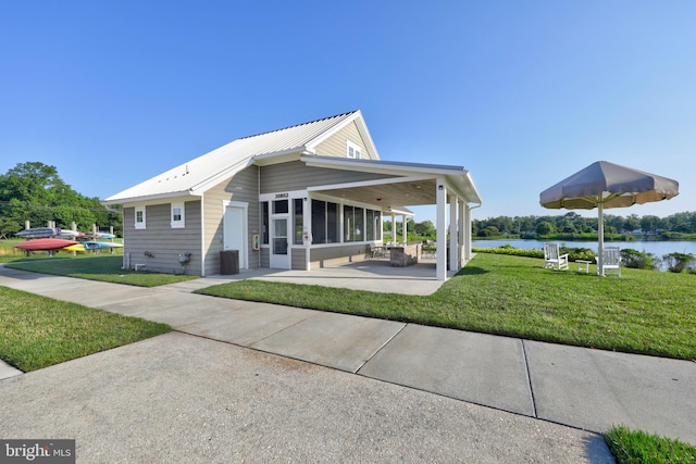 exterior space featuring a patio area, a sunroom, a yard, and a water view