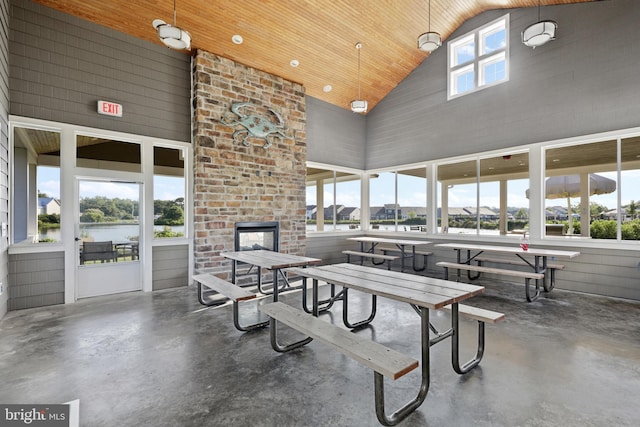 interior space with high vaulted ceiling, concrete flooring, and an outdoor brick fireplace