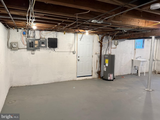 basement featuring electric panel, water heater, and sink