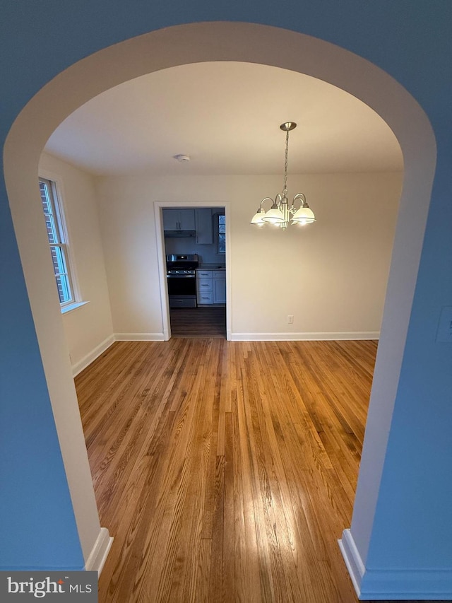 unfurnished dining area with hardwood / wood-style floors and a notable chandelier