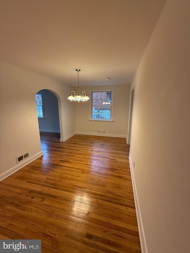 unfurnished dining area featuring a wealth of natural light, a chandelier, and hardwood / wood-style flooring