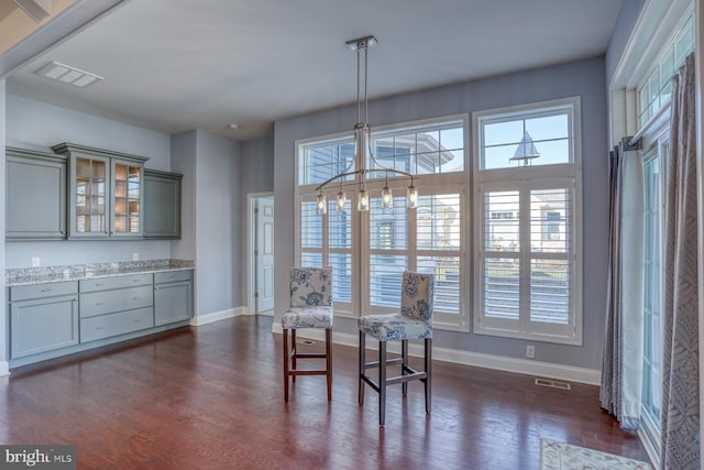 dining space with a chandelier, a wealth of natural light, and dark hardwood / wood-style flooring