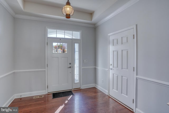 foyer with crown molding, dark wood-type flooring, and a raised ceiling