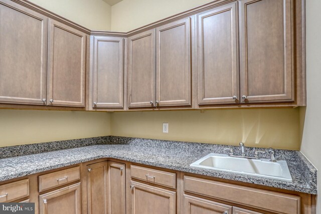 kitchen featuring light stone counters and sink