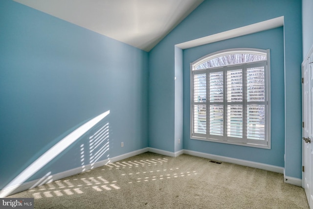 carpeted empty room with lofted ceiling