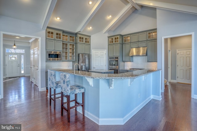 kitchen with stainless steel appliances, tasteful backsplash, light stone counters, a breakfast bar, and beam ceiling