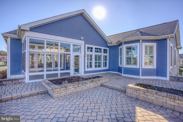 rear view of property with a sunroom and a patio area