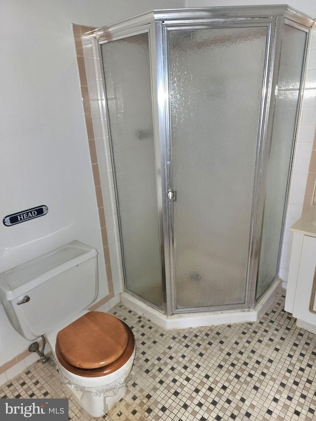 bathroom with tile patterned flooring, toilet, and a shower with shower door