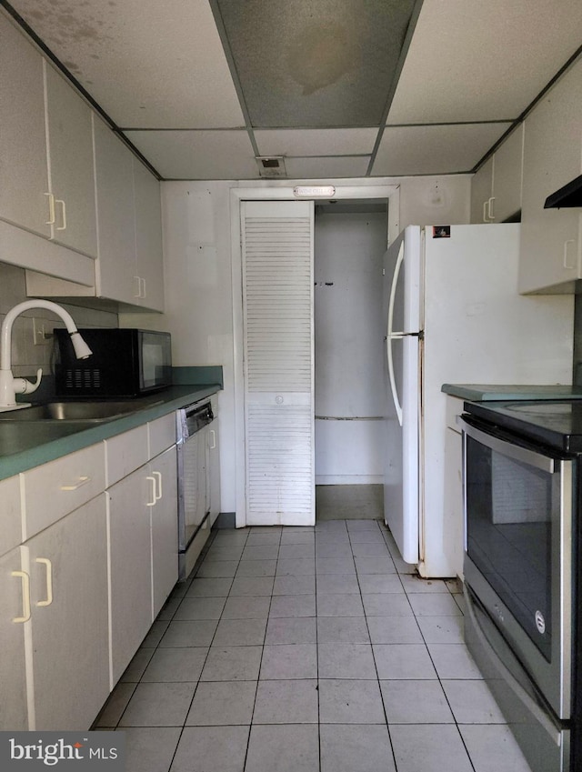 kitchen with sink, dishwasher, light tile patterned floors, stainless steel electric range, and white cabinets