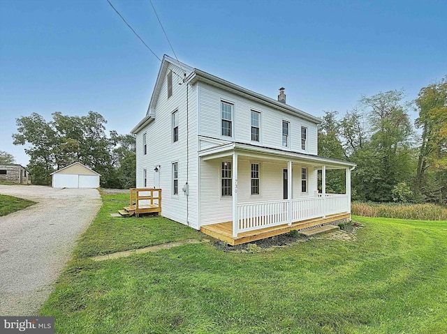 view of front of home featuring a porch, a garage, an outdoor structure, and a front lawn