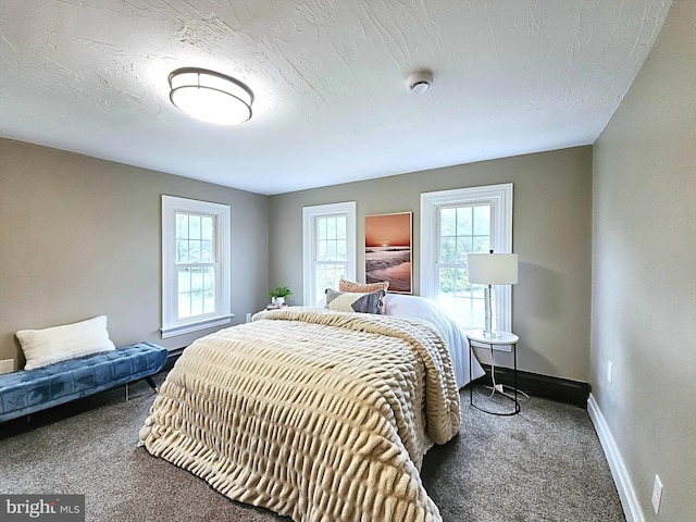 carpeted bedroom featuring a textured ceiling and multiple windows