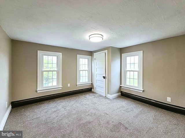 unfurnished bedroom featuring a textured ceiling, a baseboard radiator, and light colored carpet