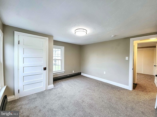 unfurnished bedroom featuring carpet flooring, a textured ceiling, and a baseboard heating unit