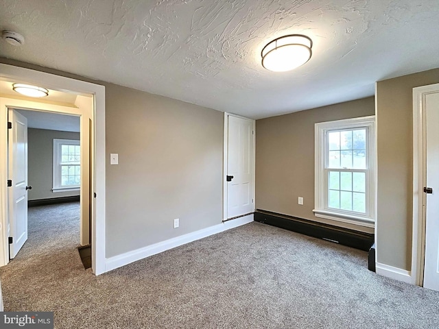 unfurnished bedroom featuring multiple windows, carpet floors, and a textured ceiling