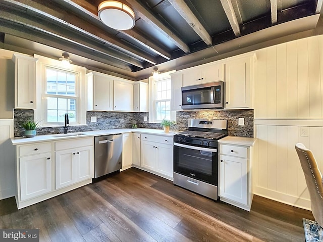 kitchen with stainless steel appliances, white cabinetry, and dark hardwood / wood-style floors