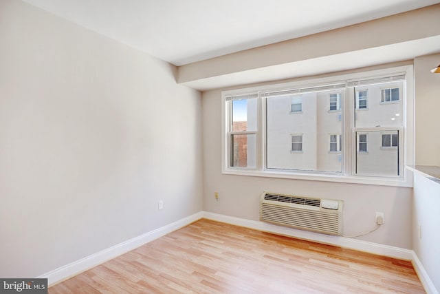 unfurnished room with a wall mounted AC and light hardwood / wood-style flooring