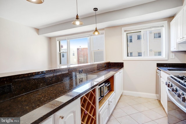 kitchen featuring hanging light fixtures, light tile patterned floors, dark stone counters, stainless steel appliances, and white cabinets