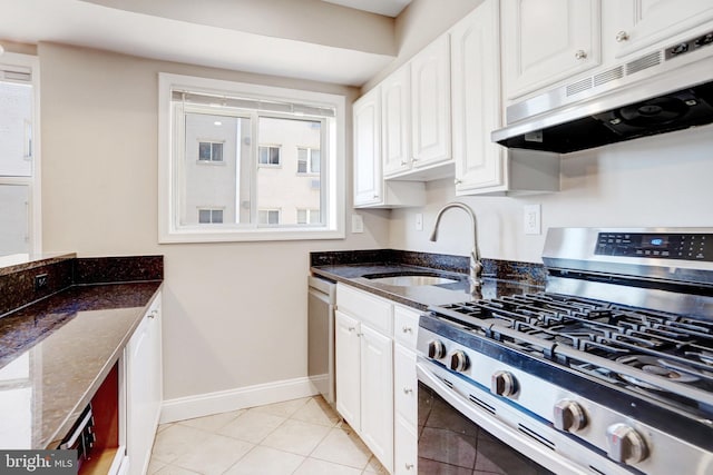 kitchen with sink, light tile patterned floors, white cabinetry, dark stone countertops, and stainless steel appliances