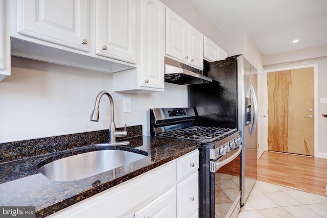 kitchen with sink, white cabinetry, dark stone countertops, light tile patterned flooring, and gas range