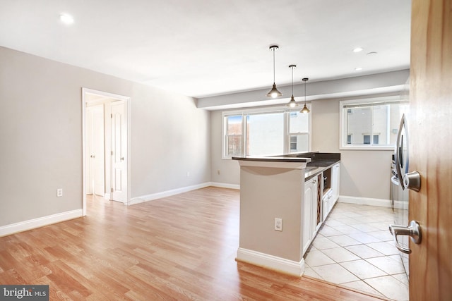 kitchen with decorative light fixtures, kitchen peninsula, a breakfast bar area, and light wood-type flooring