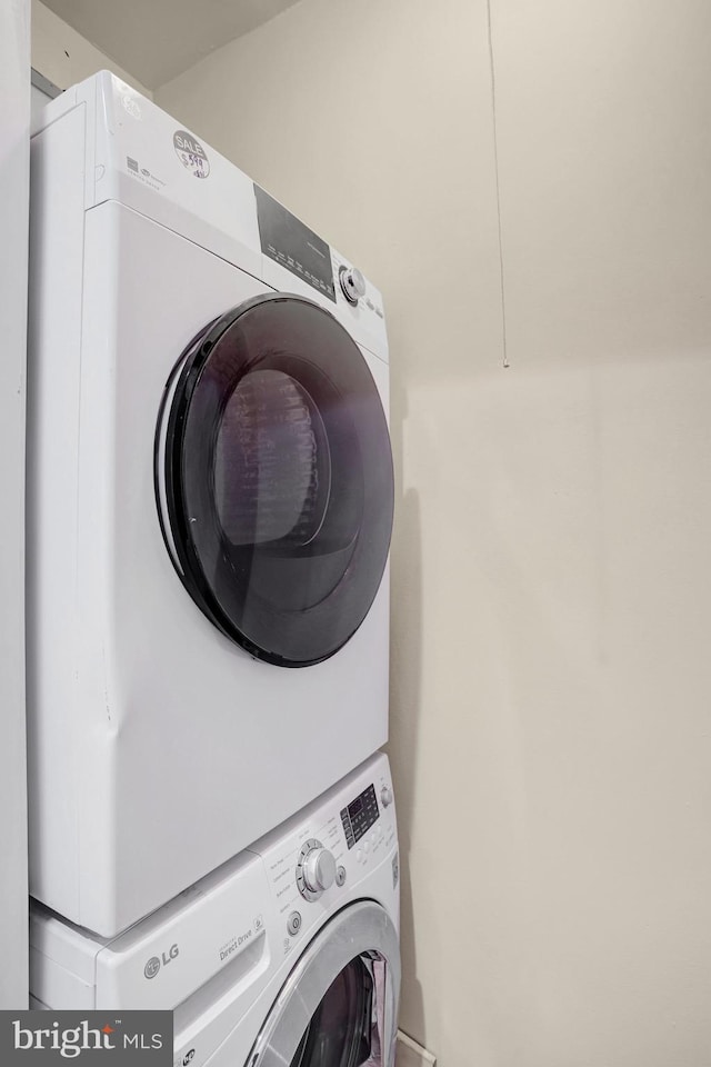 clothes washing area featuring stacked washing maching and dryer